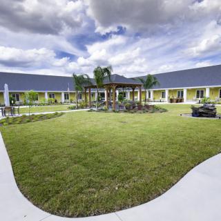 A scenic view of a courtyard garden with well-maintained lawns surrounded by a modern building and a cloudy sky above.