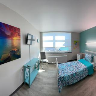 A bright and modern bedroom featuring colorful decor, a large window, and stylish furniture.