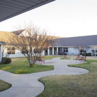 A peaceful courtyard with pathways, surrounded by a building and well-maintained landscaping.