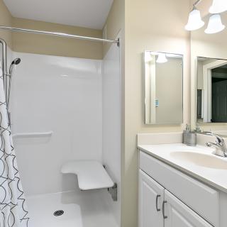 A clean and modern bathroom with a shower, sink, and mirror.