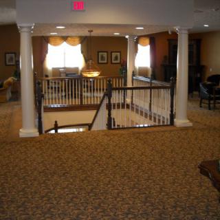 A carpeted interior space with stairs and decorative pillars.