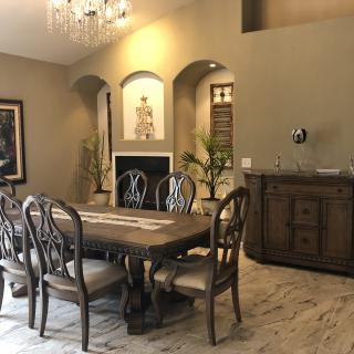 A stylish dining room featuring a wooden table with chairs, a chandelier, and decorative elements.