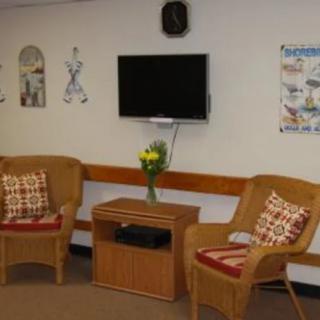 A cozy living room area with two chairs, a television, and decorative wall art.