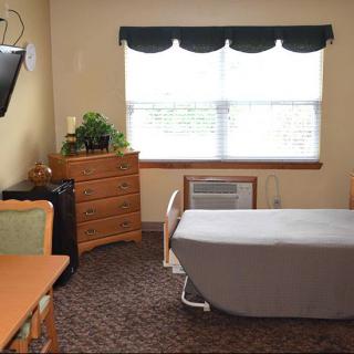 A cozy bedroom with a bed, dresser, and window letting in natural light.