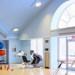 A well-lit gym interior with exercise equipment and colorful weights.
