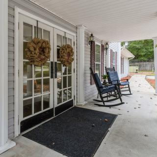 A cozy porch with rocking chairs and wreath-decorated doors.