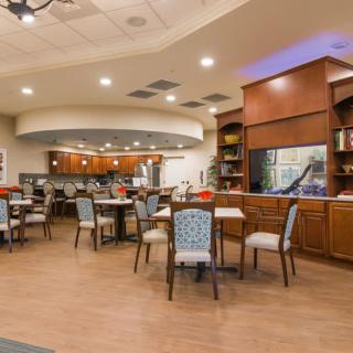 A modern dining area featuring a bar counter, tables, and chairs arranged under warm indoor lighting.