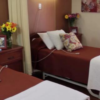 A cozy hospital room with neatly made beds and floral decorations.