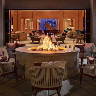 A cozy lounge area featuring a central fireplace surrounded by comfortable chairs, creating a warm and inviting atmosphere.