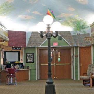 An indoor space with a decorative lamp post, ceiling mural, and seating area.