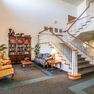 A cozy lobby space featuring a grand staircase, comfortable seating, and elegant decor.