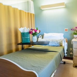 A neatly arranged hospital room with a bed and flowers on the table.