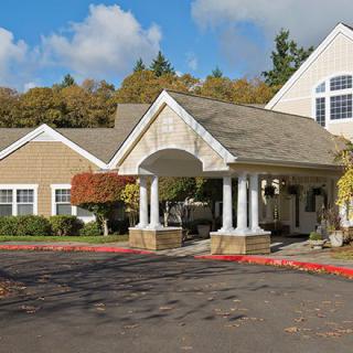 A picturesque residential building with a covered entrance and autumn foliage.