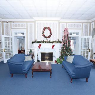 A cozy living room beautifully decorated for the Christmas season, featuring blue sofas and a festive fireplace.