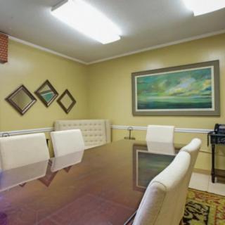 A modern conference room featuring a large table, white chairs, and decorative artwork on the walls.