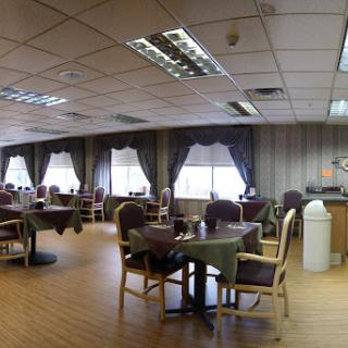 A spacious and well-lit dining area featuring tables and chairs, with large windows dressed in elegant curtains.