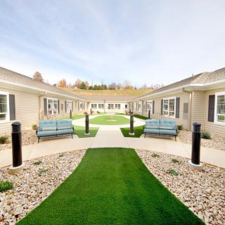 A well-maintained courtyard featuring benches, a central pathway, and surrounding buildings.