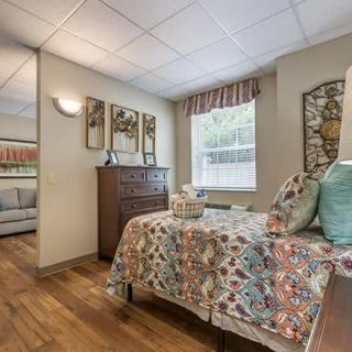 A cozy bedroom with colorful bedding and wooden flooring.