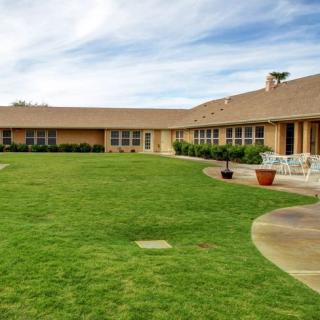 A sprawling house with a well-maintained lawn and clear skies.