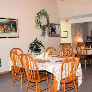 A cozy dining room with wooden tables and chairs, adorned with wall decor and greenery.