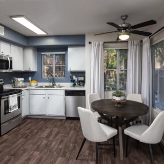 A modern kitchen with white cabinets and a cozy dining area featuring a round table and white chairs.