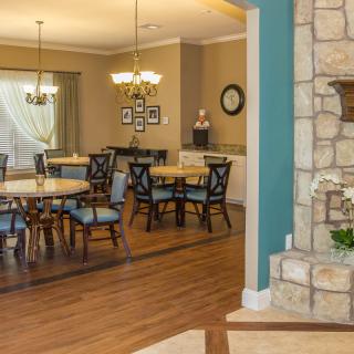 A well-decorated dining room featuring elegant chandeliers, wooden furniture, and a stone fireplace.