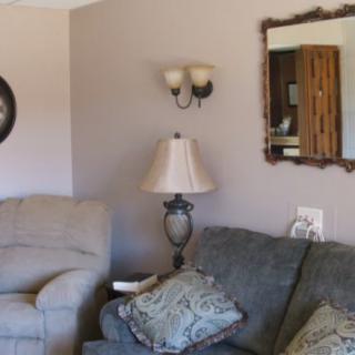 A cozy living room featuring a sofa, lamp, and wall decorations including a mirror.