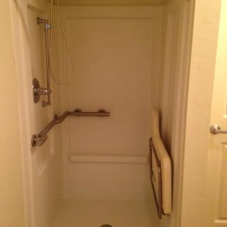 Accessible shower with grab bars and a folding seat.