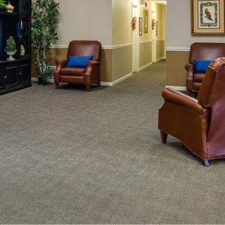 A quiet lobby area featuring leather chairs and a carpeted floor with a hallway in the background.