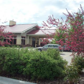 A restaurant building surrounded by blooming shrubs under a cloudy sky.