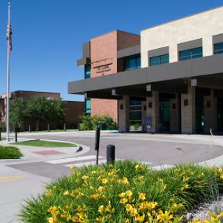 A modern public building featuring landscaped greenery and a flagpole.