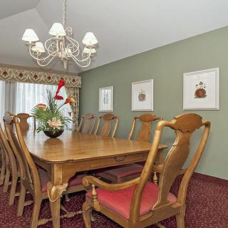 A classic dining room with a wooden table set, chandelier, and wall art.