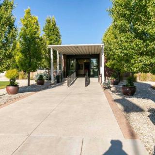 A sunny view of a building entrance surrounded by trees and landscaped paths.