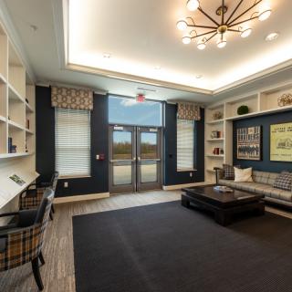 A modern lobby featuring a seating area with bookshelves, large windows, and a stylish chandelier.