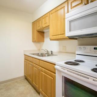 A compact kitchen featuring wooden cabinets, a sink, and essential appliances.