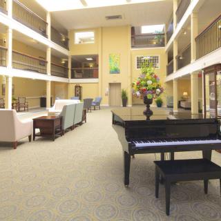 A spacious and bright lobby with a grand piano and comfortable seating arrangements.