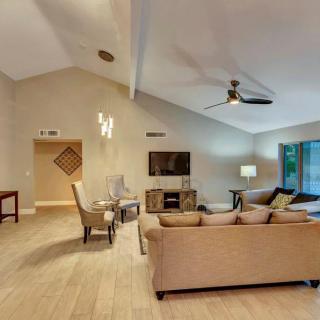 A spacious living room with modern furnishings, including a sofa, television, and ceiling fan.