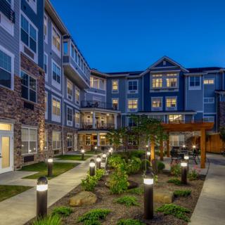 A modern apartment building illuminated at night with well-maintained landscaping.