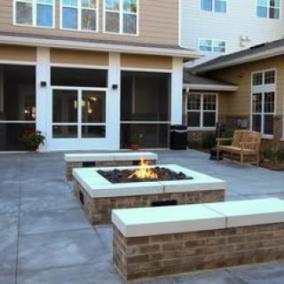 A modern outdoor courtyard featuring a central fire pit with surrounding seating.