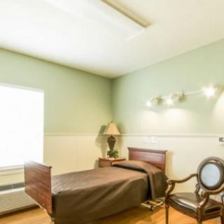 A simple and bright room with a single bed, bedside table, and lamp.