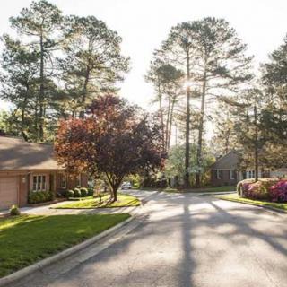 A peaceful suburban neighborhood street lined with trees and houses basking in sunlight.