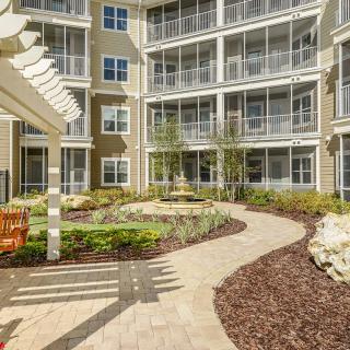 A beautifully landscaped courtyard in an apartment complex with a winding pathway and garden features.