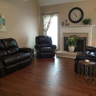 A cozy living room featuring leather furniture, a fireplace, and a decorative clock.
