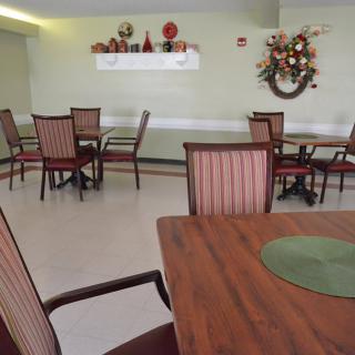 An indoor dining area with neatly arranged tables and chairs, decorated with wall art and ornaments.