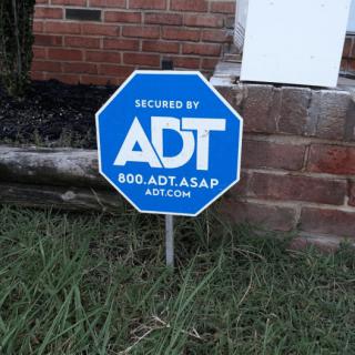A yard sign indicating ADT home security system.
