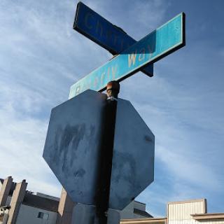 A street sign at an urban intersection against a clear blue sky.