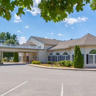 A large building with a canopy over the entrance, surrounded by trees and under a clear blue sky.
