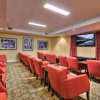 A cozy home theater room with red upholstered chairs and a large screen.