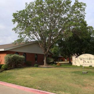 A suburban building with a tree in front and a sign on the lawn.