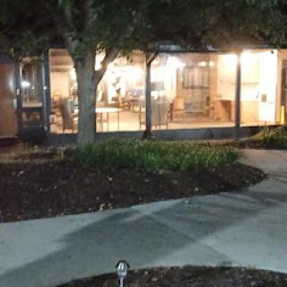 A softly lit building view at night, surrounded by a well-maintained garden and pathway.